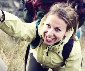 smiling female hiker being helped up a peak | Equity - the school travel people